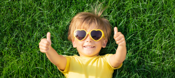child wearing sunglasses lying on grass