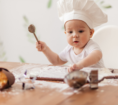 toddler cooking with chef hat and spoon