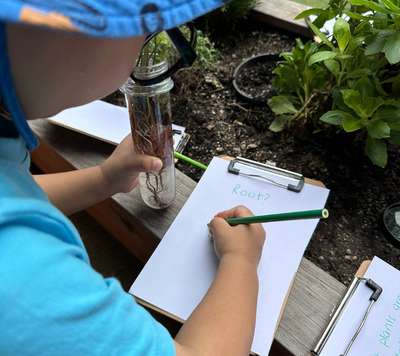 child writing notes whilst watching garden